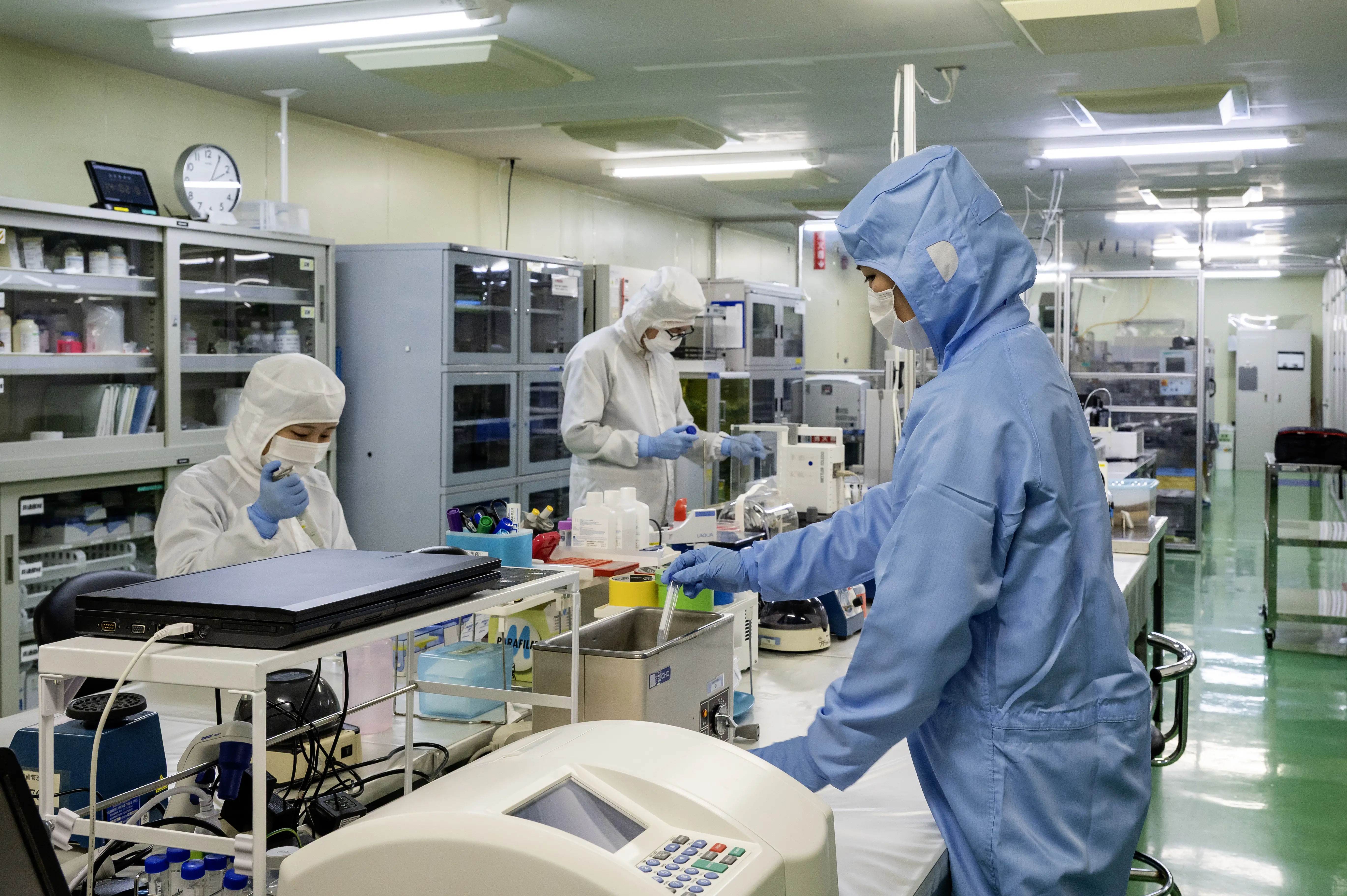 防護服姿の2名が製造ラインで操作パネルを確認している様子